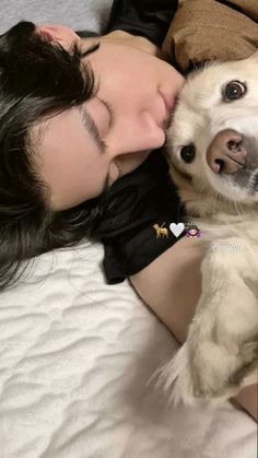 a woman laying on top of a bed next to a white and black dog with its mouth open