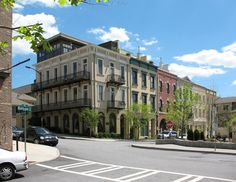 an apartment building with balconies on the second floor and several cars parked in front