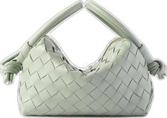 a white purse with handles and braiding on the front, sitting on a white surface