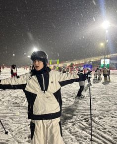 a person on skis standing in the snow at night with their arms spread out