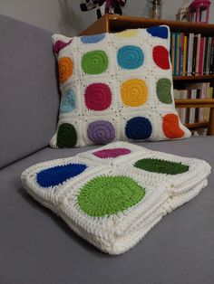 a crocheted granny blanket sitting on top of a couch next to a pillow