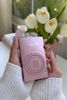 a person holding a pink camera in their hand