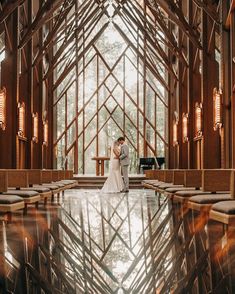 a bride and groom standing in the middle of a large room with stained glass windows