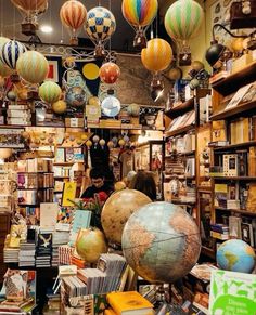 a room filled with lots of books and globes hanging from the ceiling in front of it