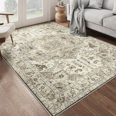 a living room area with a couch, chair and large rug on the hardwood floor