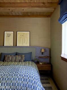 a bed sitting under two framed pictures on the wall next to a window in a bedroom