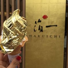 a woman is holding up an ice cream cone covered in gold foil