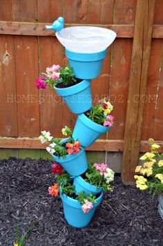 a blue birdbath with flowers growing out of it's bottom and on top