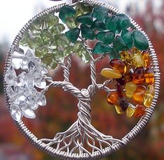 the tree of life is made out of glass beads and silver wire with green, yellow, orange, and white stones