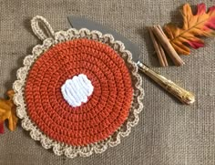 a crocheted doily with a knife and autumn leaves