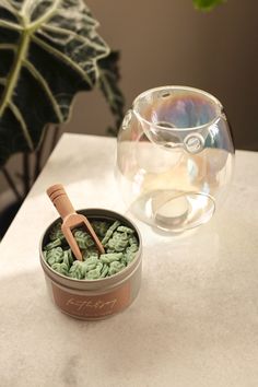 there is a bowl with green crochets in it next to a glass vase