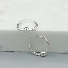 Simple sterling silver ear hoops with a silver ball. Dimensions: 1.5 x 14 mm Ball; 4mm Price listed is for a pair of ear hoops. These earrings are made of 925 hypoallergenic sterling silver. All my pieces are sent in a gift box. I can include a personal message from you if needed. You are welcome to contact me at... bhavnakwintra1956@gmail.com More hoops: https://www.etsy.com/your/shops/TheSilverGame/tools/listings/section:26305414 More earrings: https://www.etsy.com/your/shops/TheSilverGame/too Sterling Silver Hoop Piercings, Ear Piercings Minimalist, Piercings Minimalist, Pretty Silver Jewelry, Hoops Silver, Flower Ear, Gold Leaf Earrings, Floral Studs, Silver Jewelry Earrings