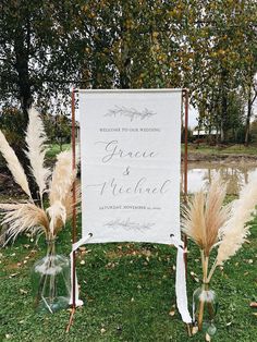 a sign that is sitting in the grass next to some flowers and water bottle vases