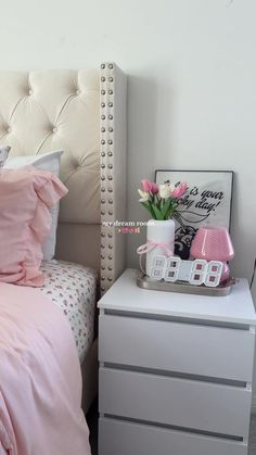 a bed with pink sheets and pillows on top of it next to a white dresser