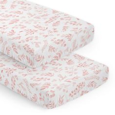 two sheets with pink leaves on them, one is folded up and the other has a pillow