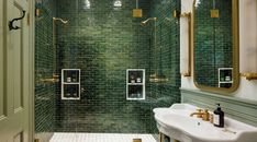 a green tiled bathroom with two sinks and mirrors