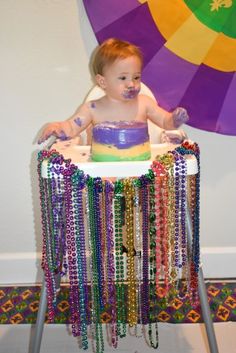 a baby sitting in a high chair covered in beads