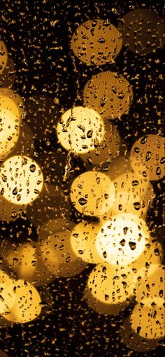 rain drops on the window and street lights in the background at night