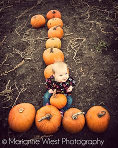 a little boy sitting in the middle of pumpkins