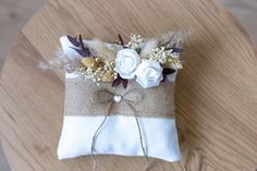 a small bag with flowers and feathers tied to it on top of a wooden table