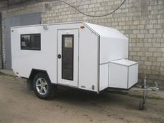 a white trailer parked in front of a brick wall