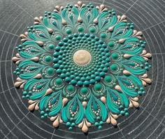 a circular design made out of green and white beads on top of a black surface