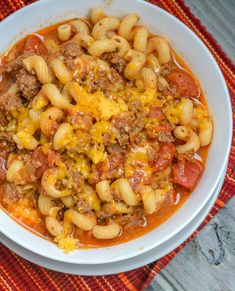 a white bowl filled with pasta and meat covered in sauce on top of a table