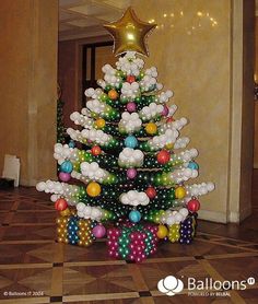 a christmas tree made out of balloons in a lobby with a star on the top