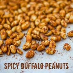 there is a pile of spicy buffalo peanuts on the table with text overlay that says spicy buffalo peanuts