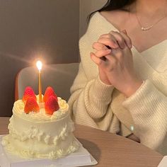 a woman sitting in front of a cake with strawberries on it