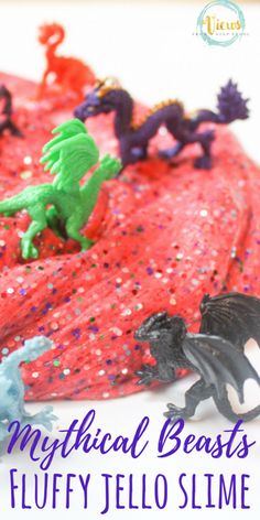 a close up of a cake with plastic toys on it and the words mythical beasts fluffy jello slime