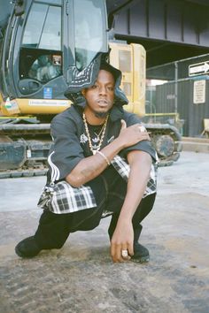 a man kneeling on the ground in front of a bulldozer with his arms crossed