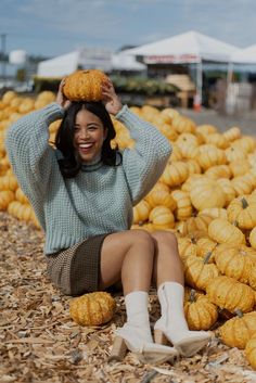 a woman sitting on the ground surrounded by pumpkins