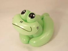 a green frog balloon sitting on top of a white table next to a black eye