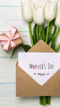 a bouquet of white tulips next to an envelope that says mother's day