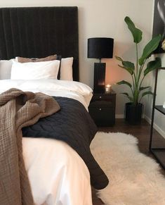 a bed with white and black sheets in a bedroom next to a lamp on a table