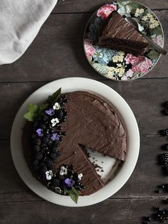 a chocolate cake sitting on top of a white plate next to a piece of cake