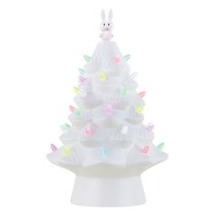 a white ceramic christmas tree with multicolored lights on it's base and a bunny figurine sitting on top