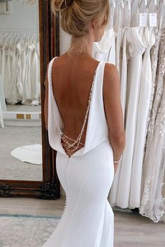 the back of a woman's white wedding dress in front of a rack of dresses