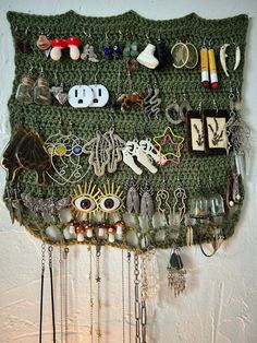 a green wall hanging with lots of jewelry on it