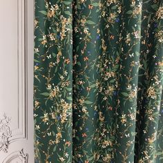 a green curtain with flowers and leaves on it