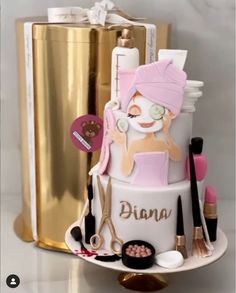 a three tiered cake decorated with cosmetics and makeup brushes on a table next to a gold container