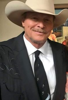 a man in a suit and tie wearing a cowboy hat