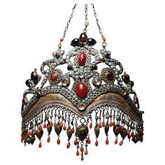 Uzbekistan, Tajikistan: a rare, old ‘bridal crown’ made of silver, gilded in parts, with turquoise coloured ornamental stones, glass, coral, and many pendants. Uzbek and Tajik women wore these ‘bridal crowns’ for the first time at their weddings and then later at important family celebrations. This luxurious jewellery was produced by Tajik craftsmen in Samarkand and Bukhara and passed on from generation to generation. The present ‘bridal crown’ consists of a sheet silver that has been cut and pu