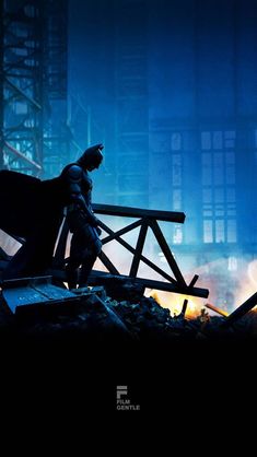 the dark knight rises from the rubble with his caped head down, standing in front of a destroyed building