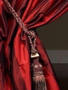 a red curtain with a tassel hanging from it's end and a chain attached to it