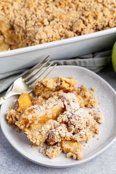 an apple crisp casserole on a white plate with a fork next to it