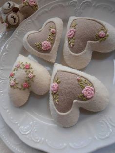 three small pieces of fabric with flowers on them sitting on a plate next to two teddy bears