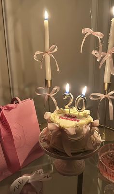 a birthday cake on a table with candles in the shape of number 20 and pink bag