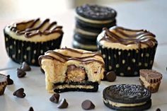 several oreo cookies and chocolate cupcakes on a white surface with one cookie cut in half